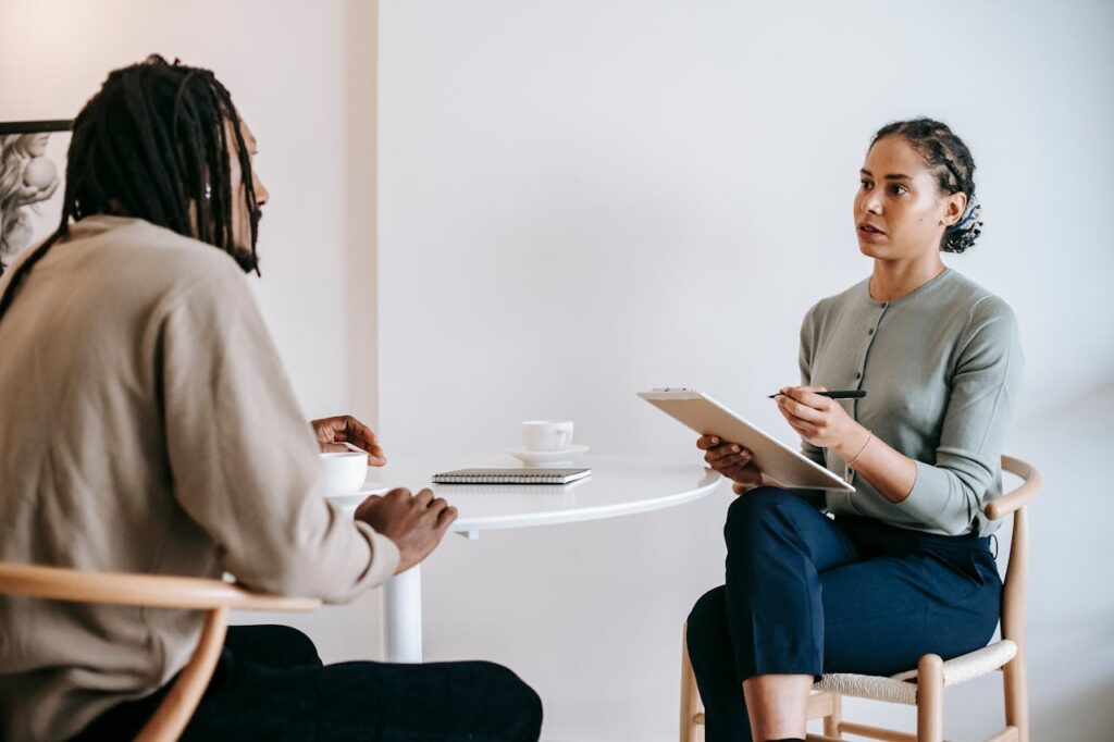 pexels-photo-5699479 Ethnic female psychotherapist listening to black clients explanation